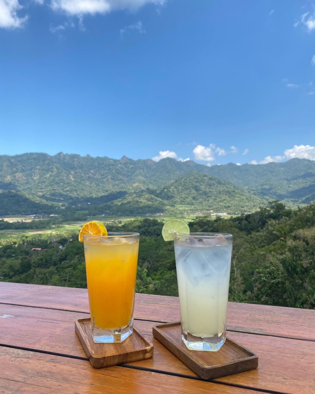 Dua gelas minuman segar di meja kayu Kedai Bukit Rhema dengan latar Perbukitan Menoreh
